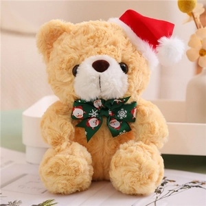 Close-up of a brown teddy bear wearing a red Christmas hat and green festive bowtie