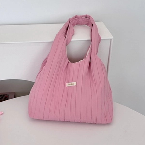 Detailed view of pink pleated fabric shoulder bag with minimalist rectangular woven label