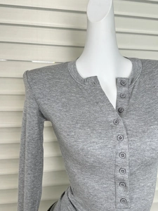Détail du col d'un haut gris Henley en maille avec patte de boutonnage et texture fine