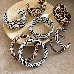 Fashionable leopard and zebra print leather open bangles displayed on a stone tray