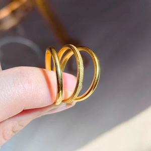 Macro detail of three 18k gold-plated titanium steel rings with polished and frosted finishes