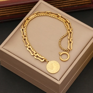Detailed macro view of a gold double-layer chain bracelet with a carved coin pendant