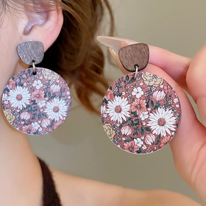 Détail de boucles d'oreilles rondes en bois vintage avec motif floral et tige en argent