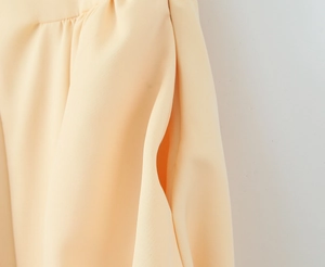 Détail de la poche latérale et de la texture du tissu de cette robe élégante abricot