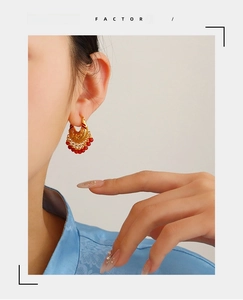 Close-up of model wearing retro Chinese style gold filigree earrings with red beads
