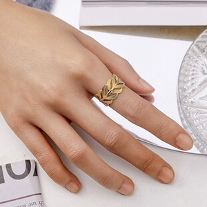 Detail of elegant gold hollow leaf ring on finger with artistic mirror background