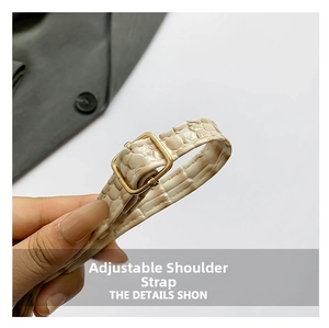 Detail of adjustable beige crocodile pattern strap with a polished gold metal buckle