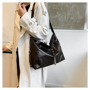 Detailed view of black leather tote bag featuring gold rivets and elegant urban texture