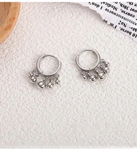 Detailed shot of 925 silver hoop earrings with five polished beads on a textured surface