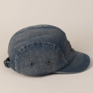 Detailweergave van de gewassen blauwe denim baseballpet met metalen oogjes en verstelbare gesp