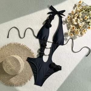 Detail of black halter swimsuit featuring 3D floral accents and pearl beaded cut-outs