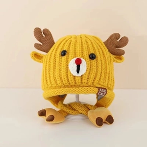 Close-up of yellow knit baby deer hat with brown antlers and plush earflaps detail