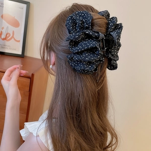 Gros plan d'une pince à cheveux en tissu noir à pois blancs sur la chevelure d'une femme