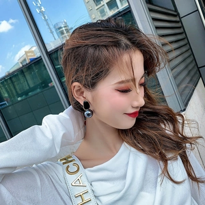 Detail of minimalist bunny ear geometric pearl earrings worn by a model in urban setting