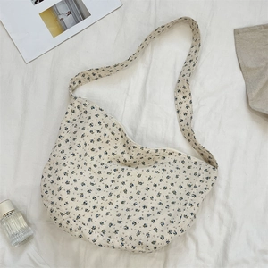 Detailed shot of crescent floral canvas bag with blue flowers on white fabric backdrop