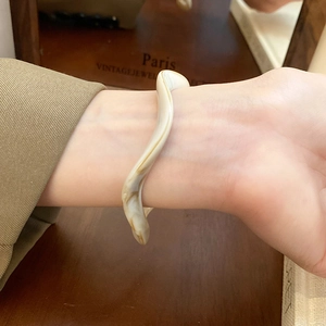 Macro detail of wave resin bangle showing creamy marble texture and vintage amber pattern