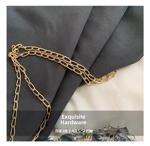Close-up of polished gold chain strap on a shimmering silver sequin crossbody bag