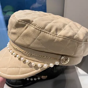 Elegant beige quilted newsboy cap with pearl chain and gold metal link details