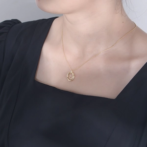 Macro shot of gold double-ring necklace with zircon inlay on a female model