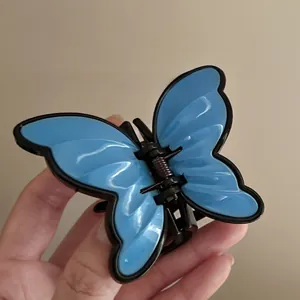 Detail shot of a blue butterfly hair claw clip with black edges and metal spring