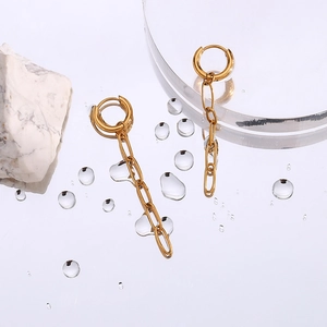 Detail of gold paperclip chain earrings on mirror with stones and water droplets
