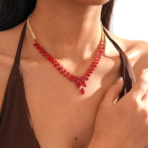 Détail d'un collier doré avec cristaux rouges marquises porté élégamment au cou