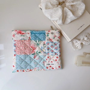 Pochette en patchwork matelassé fleuri avec étiquette sur fond blanc épuré