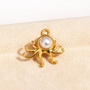 Macro detail of a golden octopus pendant with a white pearl on beige velvet surface