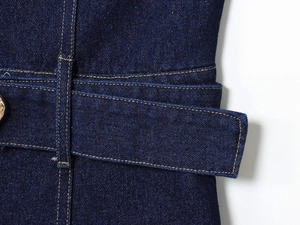 Detailed close-up of dark blue denim dress waist with contrast stitching and metal belt buckle