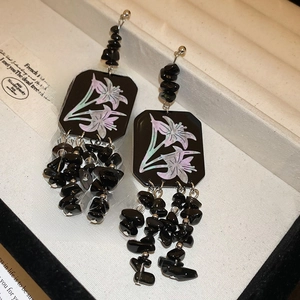 Detail of black lily flower earrings with matching dark stone tassels and silver hooks