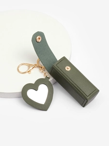 Detailed macro view of an open green leather lipstick case with heart mirror and gold key ring
