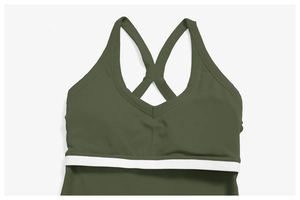 Détail du haut de sport vert olive avec bretelles en X et bande contrastée blanche
