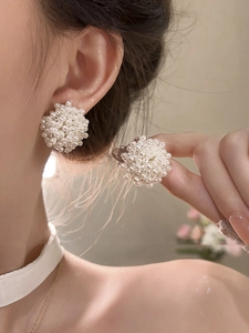 Close-up of elegant French vintage pearl cluster earrings worn on a person ear