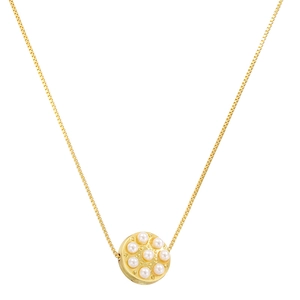 Detail of elegant gold circular pendant necklace with inlaid white pearls on flat white surface