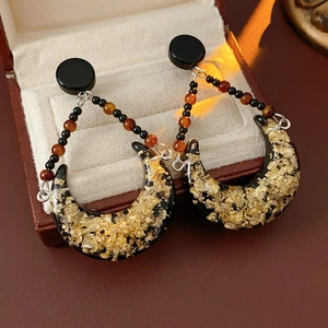 Detailed close-up of vintage resin crescent earrings with gold foil in a jewelry box