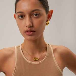 Close-up of golden spiral pendant necklace and matching earrings on a female model