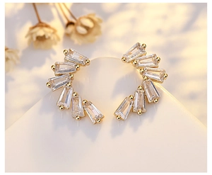 Detail shot of elegant gold earrings with five rectangular zircons in a curved layout