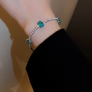 Detailed shot of an elegant silver bracelet featuring oval green crystals and zircons