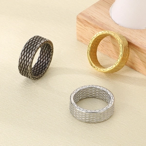Detailed view of textured stainless steel rings in gold, silver, and gun black finishes