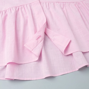 Detailansicht der rosa Rüschentop mit plissierter Leinentextur und Knopfloch-Verarbeitung
