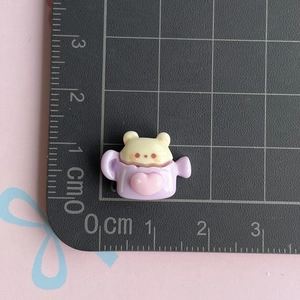 Macro detail of a 1.5cm resin beige bear in a purple teapot charm for DIY crafts