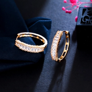 Detailed view of gold hoop earrings with baguette-cut cubic zirconia on velvet
