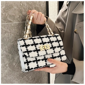 Close-up of black and white tweed crossbody bag with gold chain strap and texture