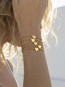 Chic gold heart charm bracelet set on wrist in natural outdoor light showing stacking effect