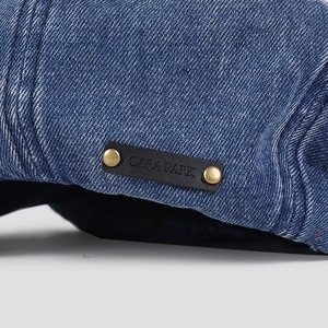 Macro shot of dark blue denim hat with a leather logo tag and vintage gold metal rivets