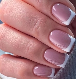 Macro shot of glossy French tip press-on nails with soft pink base and white square edges