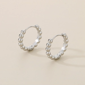 Close-up of silver stainless steel hoop earrings with minimalist beaded texture detail