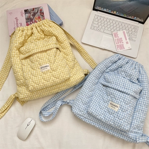 Close-up of quilted heart pattern and drawstring on yellow and blue plaid backpacks