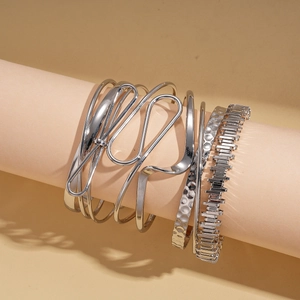 Modern set of four irregular geometric silver metal bracelets on a minimalist display stand