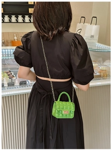 Detail of neon green quilted mini bag with golden chain and twist lock on a model